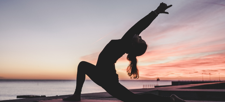 A woman enrolled in prenatal yoga classes Dubai has to offer practicing this ancient practice during sunset