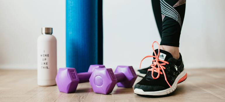 Woman's feet in running shoes near exercise equipment representing Strength and Conditioning Training for Women in Fujairah