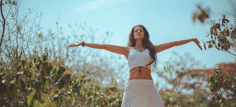 A woman in nature spreading her arms representing Improving Sleep Quality Through Exercise
