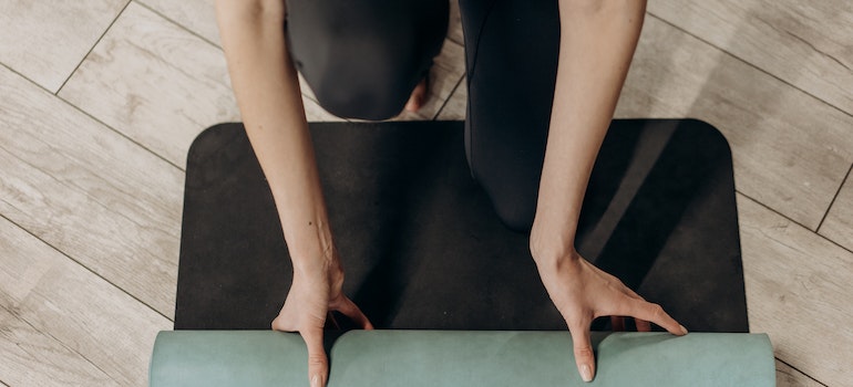 A person rolling a yoga mat needed for Improving Sleep Quality Through Exercise