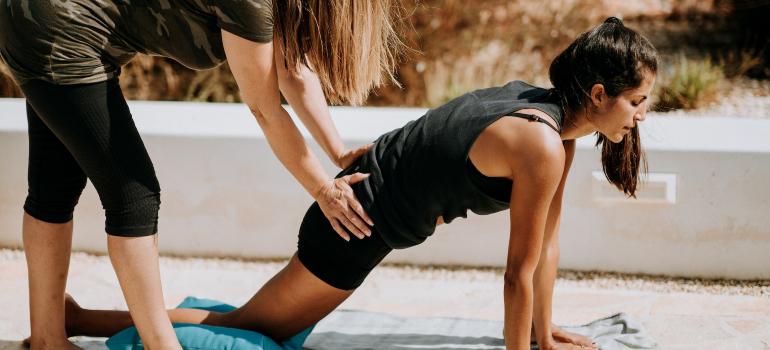 A female personal trainer ajman helping a woman with an injury work out
