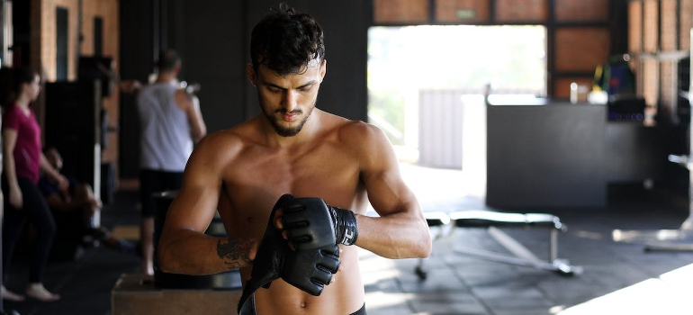 A man wearing black leather gloves and working on ways to maintain fitness levels while traveling in UAE with boxing training UAE.