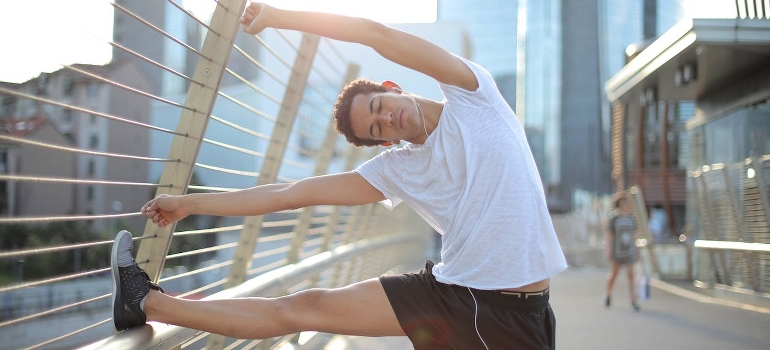 Young man doing stretching outdoors representing How to Choose a Weight Loss Trainer in Abu Dhabi