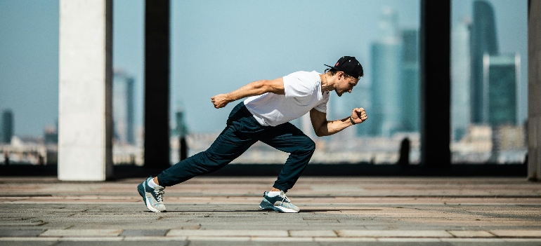 Man in White T-shirt and Black Pants In A Running Position