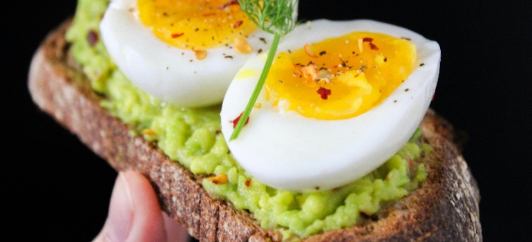 a person holding an avocado toast with an egg after reading healthy eating tips for weight loss in Dubai