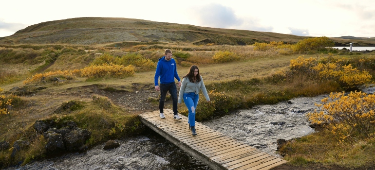 A couple walking across a bridge over a stream