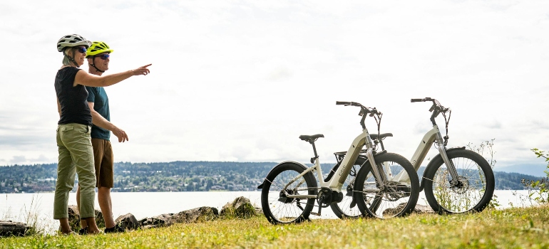 A Couple Standing on Green Grass Near Electric Bikes