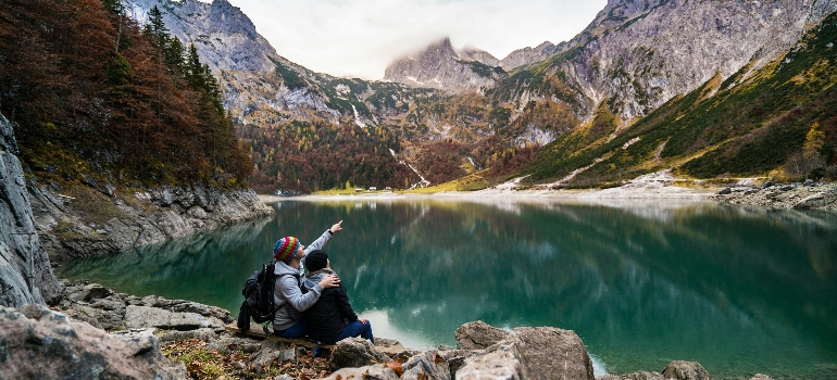 A couple sitting on a rock beside the lake
