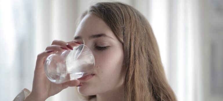 A woman drinking water after understanding the role of hydration in weight loss for Dubai residents