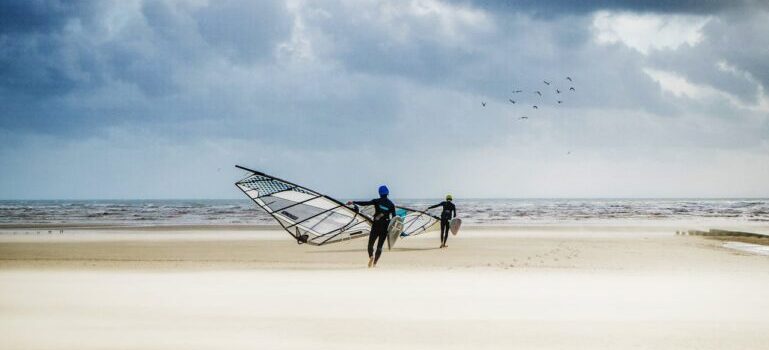 people walking and holding surf boards