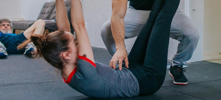 Fitness trainer helps client perform exercise correctly