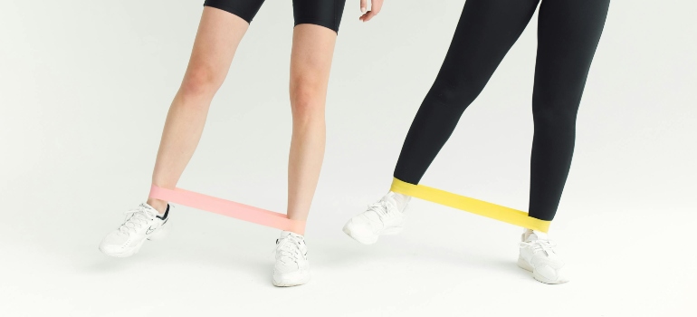 Two girls do one out of five best resistance band exercises for strength training in Dubai