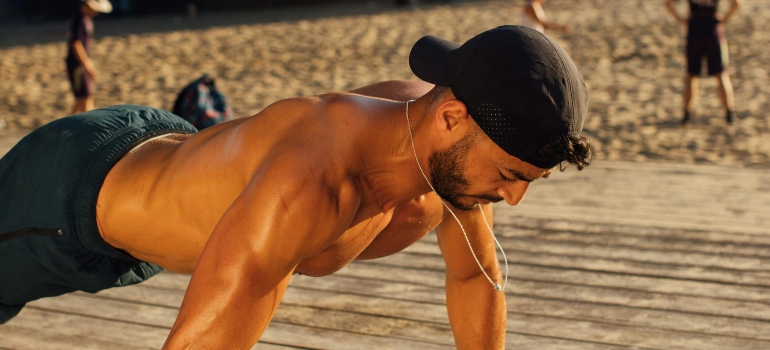 A man is doing push-ups on the Dubai beach.