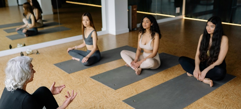 4 women sitting on mats before training