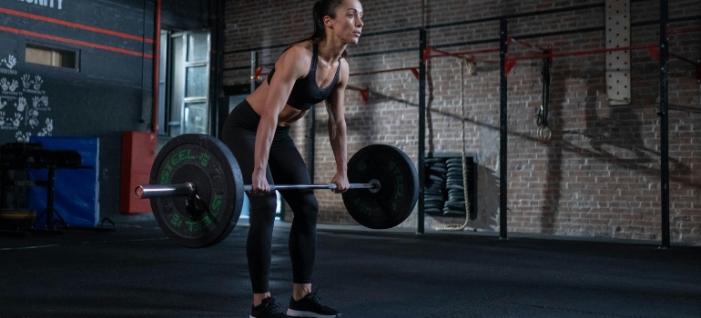 Woman in Black Sportswear Lifting a Barbell