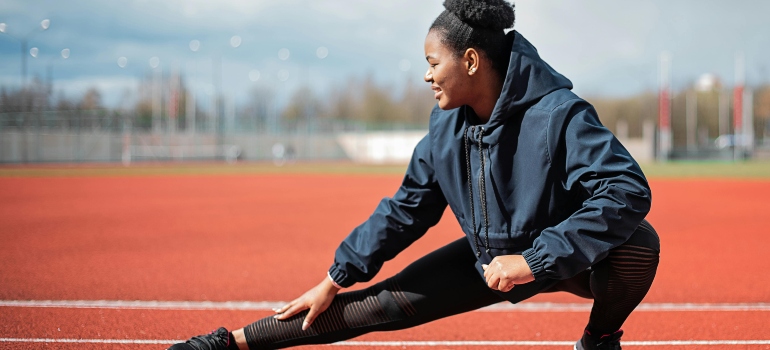 A woman is stretching outdoors in one of the best calisthenics parks in Abu Dhabi.