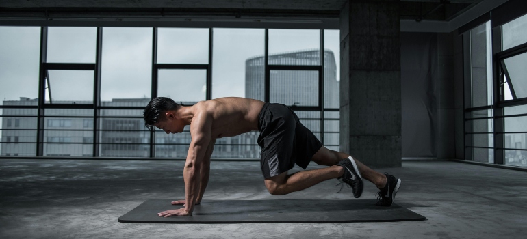 A man is doing exercises in the gym, thinking about popular strength training routines in Abu Dhabi.