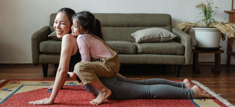 Busy mom doing a yoga routine with her daughter, combining playtime with workout