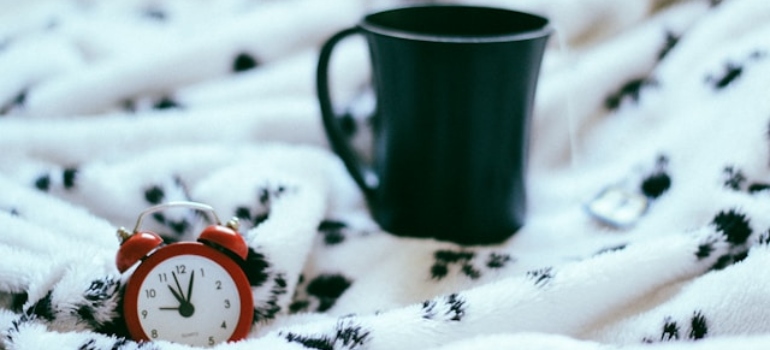 Mug and alarm clock on a bed