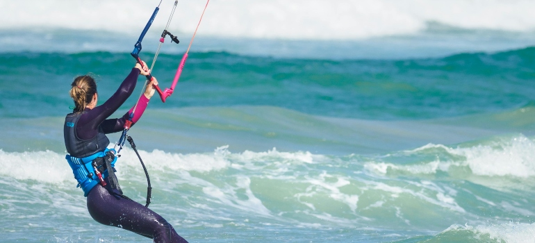 A woman holding a rope while riding a boat in the sea, thinking about safety tips before you learn to windsurf in Dubai.
