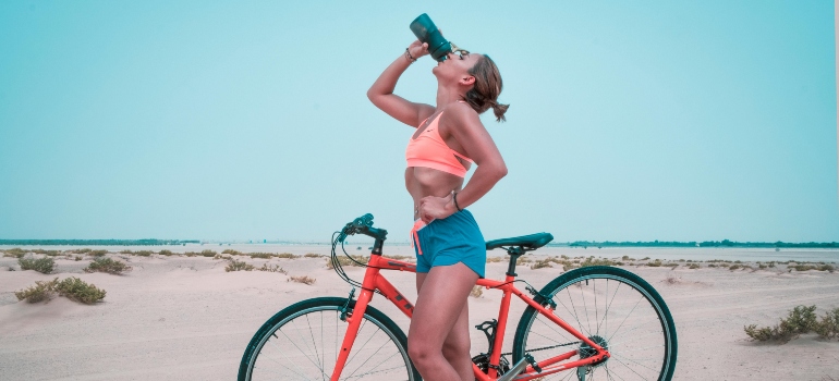 Woman drinking water during a cycling break to stay hydrated under the sun in Sharjah