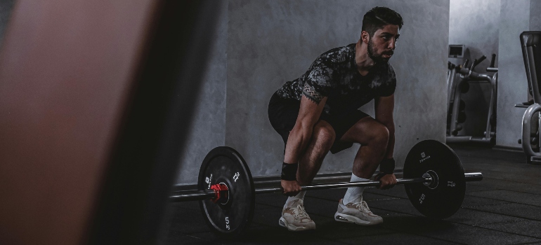 Man preparing to lift a barbell during a strength training session in the gym.