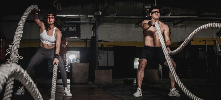 Man and woman training with battle ropes, showing Combining Yoga and Strength Training for improved performance.