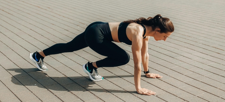 Woman doing a mountain climber exercise outdoors on a sunny day.