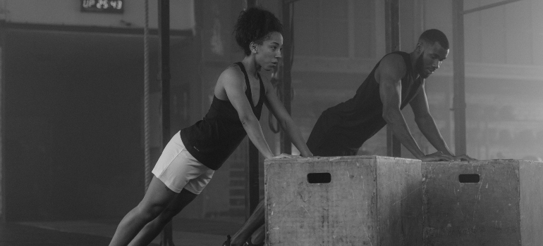 Two athletes performing incline push-ups together in a fitness studio.