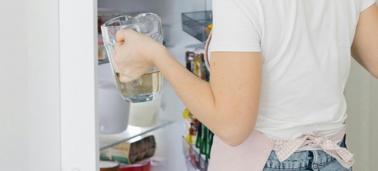 Woman storing prepared meals in fridge to keep meals fresh longer for weekly meal prep